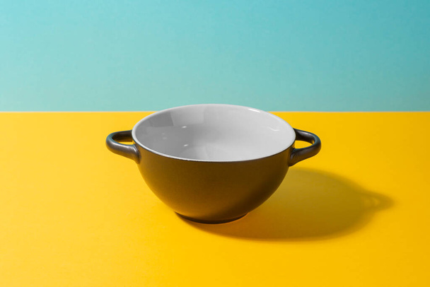 Black deep ceramic bowl on colorful background - Фото, изображение