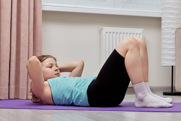 Cute beautiful girl performs abs exercises at home. - Zdjęcie, obraz