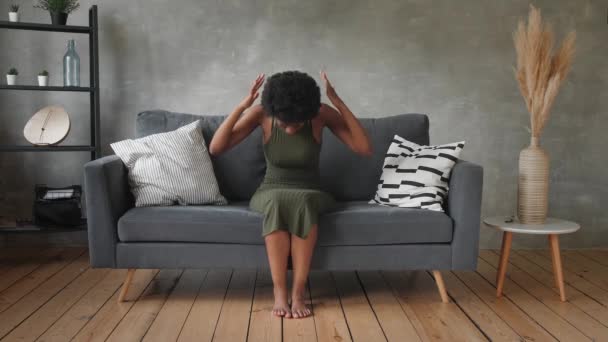Afro americká žena s přemýšlivým obličejem sedí na gauči - Záběry, video