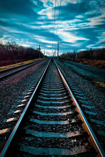 chemin de fer, rails et traverses sans trains gros plan, sur un beau ciel nuageux au coucher du soleil - Photo, image