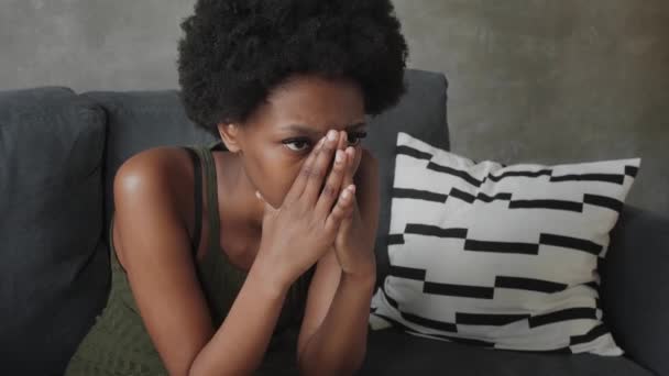 Αφρο-αμερικανική γυναίκα με στοχαστικό πρόσωπο κάθεται στον καναπέ - Πλάνα, βίντεο