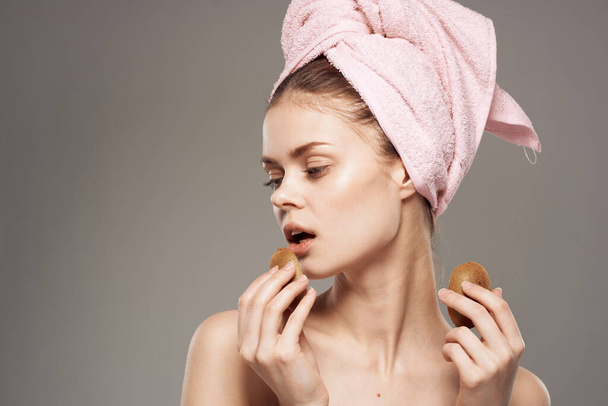 beautiful woman with pink towel on her head naked shoulders kiwi in hands health skin care - Photo, Image
