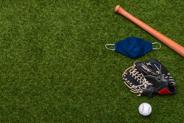 Bate de béisbol, pelota, guante y máscara aislados en un campo de hierba. Temporada de béisbol con máscara facial. Concepto deportivo seguro - Foto, imagen