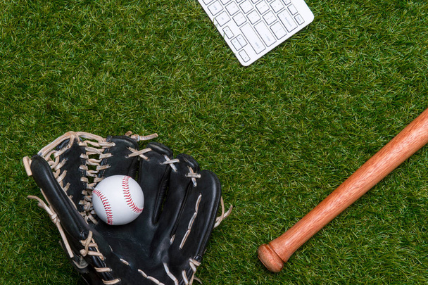 Beyzbol sopası, top, eldiven ve bilgisayar klavyesi çimlerin üzerinde izole edilmiş. Düz yerde, üst tarafta. Spor evi ve online spor konsepti - Fotoğraf, Görsel