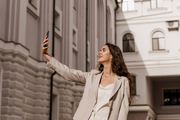 Νεαρή επιχειρηματίας κάνει selfie απομονωμένη στην πόλη. Ελκυστική κοπέλα που μιλάει με τους φίλους της με βιντεοκλήσεις. Σύνδεση on-line με την οικογένεια. Μείνε σπίτι. - Φωτογραφία, εικόνα