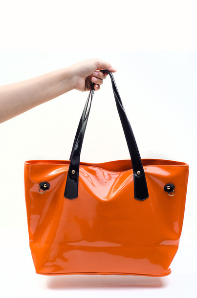 Mano sosteniendo bolso de mujer naranja
 - Foto, Imagen