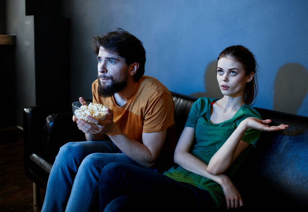Мужчины и женщины на диване в темной комнате смотрят фильм ужасов - Фото, изображение