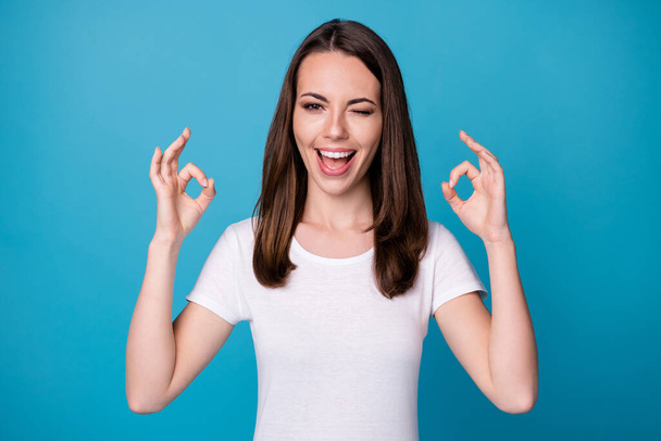 Portrait of excited girl show okay symbol recommend suggest select adverts promo wink blink wear good look outfit isolated over blue color background - Photo, image
