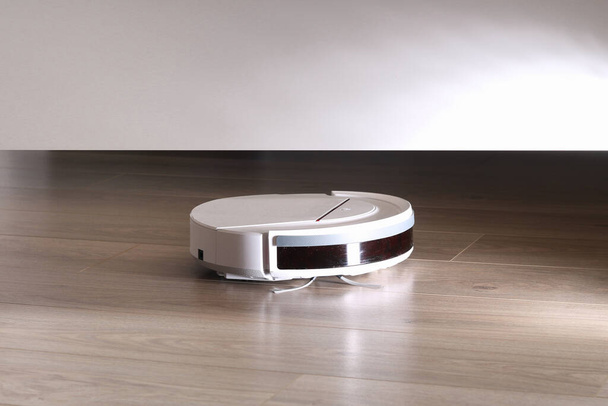 The robot vacuum cleaner cleans under the bed. High quality photo - Photo, Image
