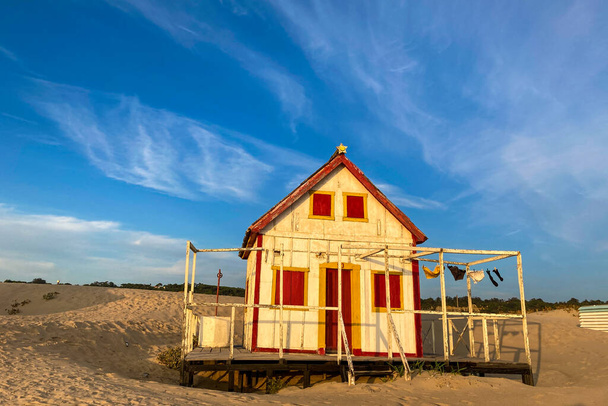 Bela casa de madeira característica ao longo da praia na Costa da Caparica, em Lisboa, Portugal. Pequena aldeia na praia ao pôr do sol de frente para o Oceano Atlântico, edifício abandonado na praia - Foto, Imagem
