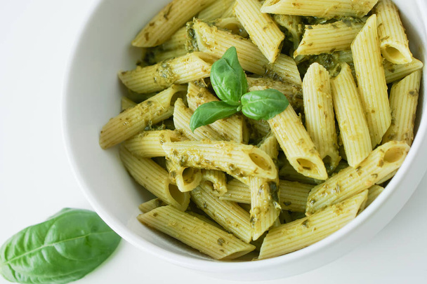 Zelfgemaakte Italiaanse penne pasta noodle koken voedsel met biologische groene verse basilicum blad kaas noten pesto saus gezonde maaltijd voor veganistische vegetarische - Foto, afbeelding