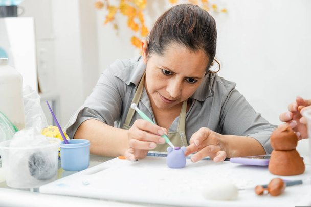 Femme hispanique travaillant dans sa pâtisserie - femme latine travaillant avec fondeur pour décorer un gâteau - chef pâtissier entrepreneur - femme faisant de l'artisanat avec de l'argile - Photo, image