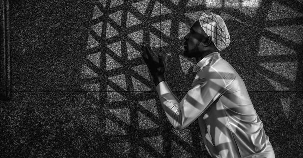 Мусульманин, совершающий обряд поклонения и молящийся за благословение Аллаха в мечети во время исламского рамадана в черно-белом - Фото, изображение
