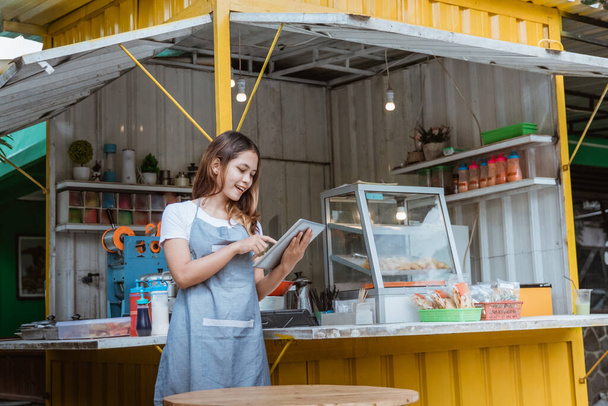 woman taking online order at her small stall shop - Photo, Image
