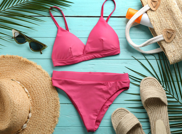 Beautiful pink bikini and beach accessories on light blue wooden background, flat lay - Фото, изображение