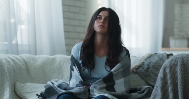 Jeune femme indifférente assise enveloppée de plaid, se sentant non motivée et désintéressée, au ralenti - Séquence, vidéo