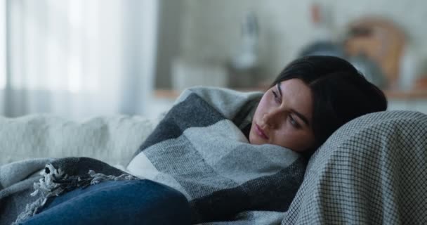 Szomorú depressziós fiatal nő fekszik egyedül a kanapén kockás, fáradtnak érzi magát magányos sebezhető és gyenge - Felvétel, videó