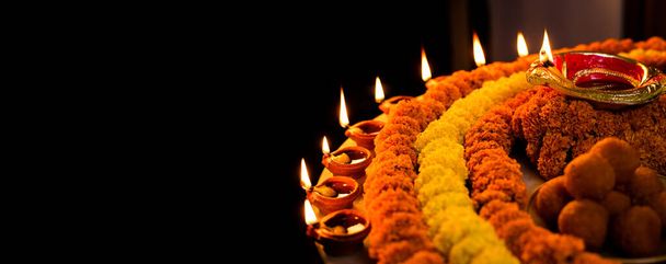 Diwali brillante Diya y flores dispuestas en forma circular formando un diseño con espacio de copia, enfoque selectivo con espacio en blanco extra para el texto - Foto, Imagen