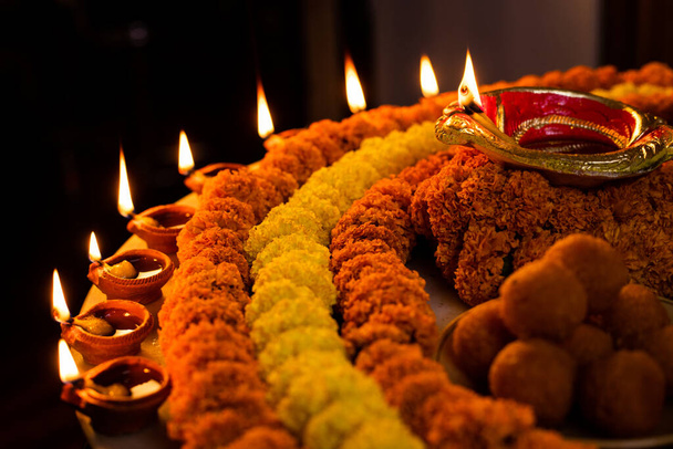 Diwali brillante Diya y flores dispuestas en forma circular formando un diseño con espacio de copia, enfoque selectivo con espacio en blanco extra para el texto - Foto, Imagen