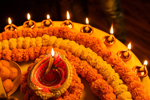 Happy Diwali - Clay Diya λαμπτήρες άναψε κατά τη διάρκεια Dipavali, ινδουιστικό φεστιβάλ των φώτων γιορτή. Πολύχρωμο παραδοσιακό φωτιστικό πετρελαίου diya και γλυκά σε μαρμάρινο φόντο - Φωτογραφία, εικόνα