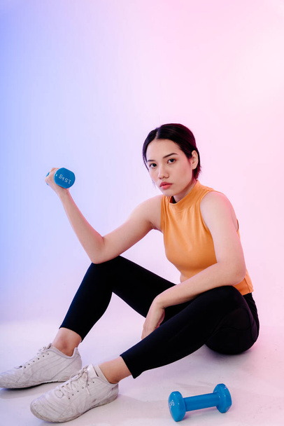 Portrait of healthy asian woman sit on floor and work out with dumbbells. - Foto, Imagen