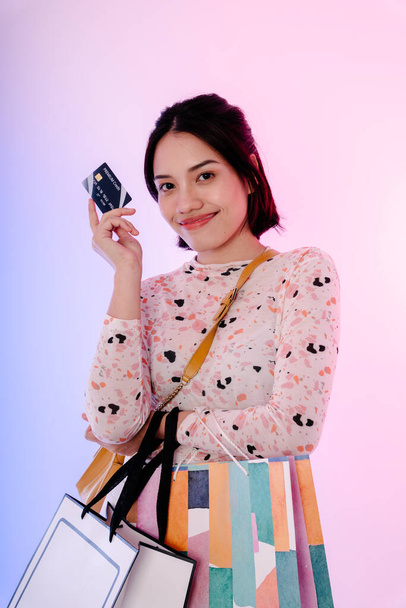 Glückliche asiatische Frau schwarze Haare genießen Shopping mit Kreditkarte. Einkaufstüten täuschen Design vor. - Foto, Bild