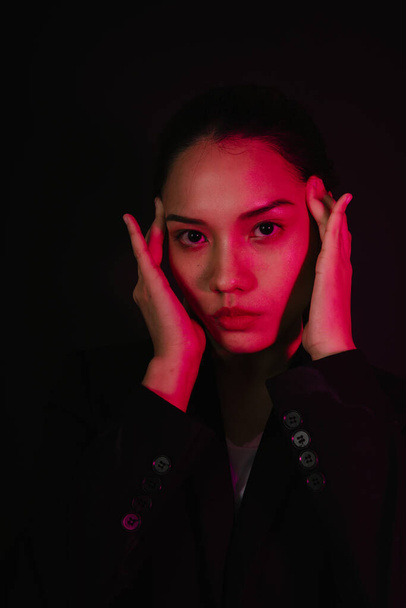 Close up portrait of young asian dark hair woman in neon light on black background. - Photo, Image