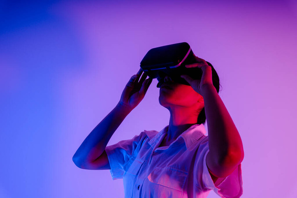 Πορτρέτο της νεαρής Ασιάτισσας που χρησιμοποιεί γυαλιά VR για να παίξει παιχνίδι και βίντεο. - Φωτογραφία, εικόνα