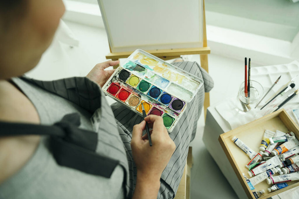 Професійна художниця використовує кольорову палітру на полотні
. - Фото, зображення