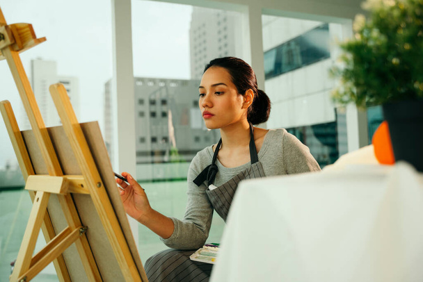 Female artist painting colour oil on canvas easel in studio. - 写真・画像