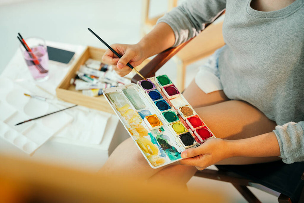 Professionele vrouwelijke kunstenaar met kleurenpalet schilderen op doek. - Foto, afbeelding