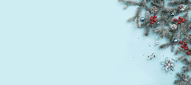 Весёлая рождественская рама из белых еловых ветвей на синем фоне с серебряными украшениями, блестками, боке, светом, блестками. Рождественские и новогодние открытки, зимние праздники. Плоский, вид сверху, баннер - Фото, изображение