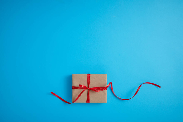Kırmızı fiyonklu hediye kutusu mavi arka planda, üst manzara, tatil arka planı - Fotoğraf, Görsel