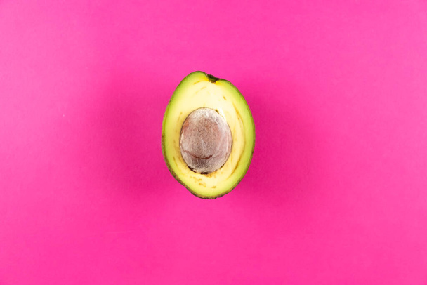 Half fresh avocado fruit on pink background - Valokuva, kuva