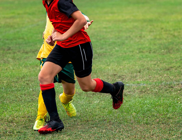 若いサッカー選手が試合中にフィールドでボールを追いかける - 写真・画像