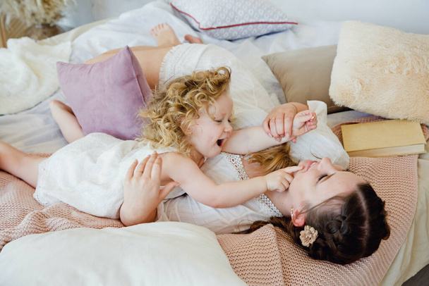 Happy loving family. Mother and daughter play and hug. The morning together. Happy games in the bedroom. - Fotografie, Obrázek