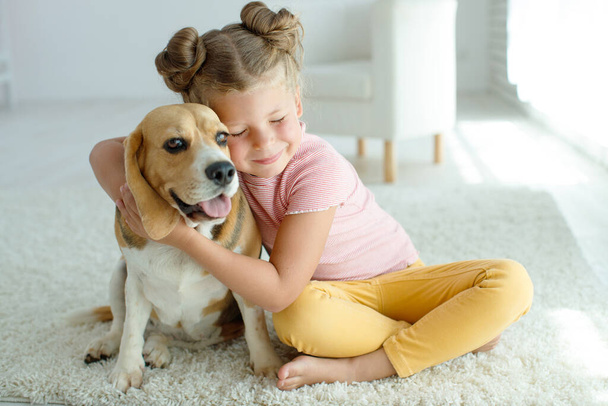 Happy child with a dog. Portrait of a girl with a pet. Beagle licks with a teenager. - Photo, Image