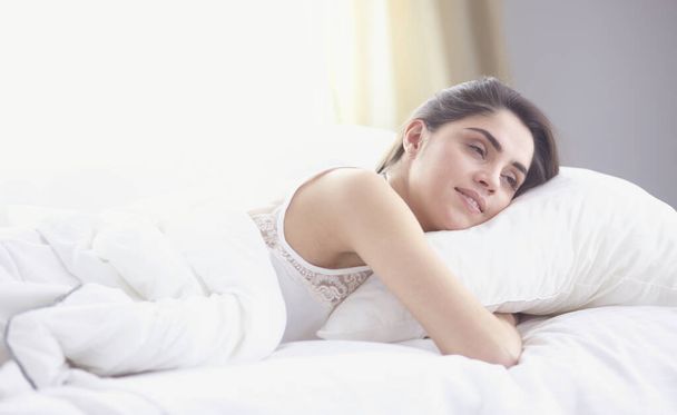 mooie jonge vrouw koesteren in bed in de ochtend. Mooi Model gezicht ziet er sexy in de camera - Foto, afbeelding