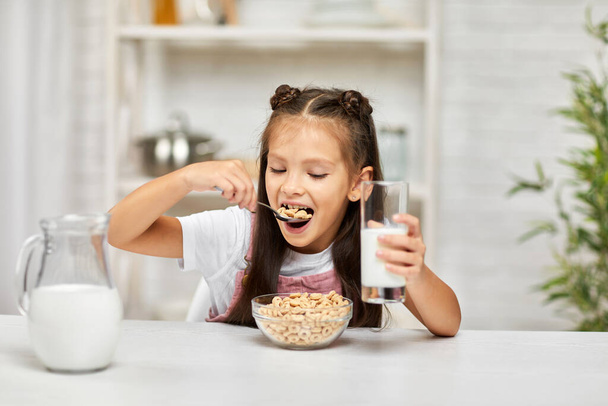 cute little girl eating breakfast: cereal with the milk - Foto, Bild