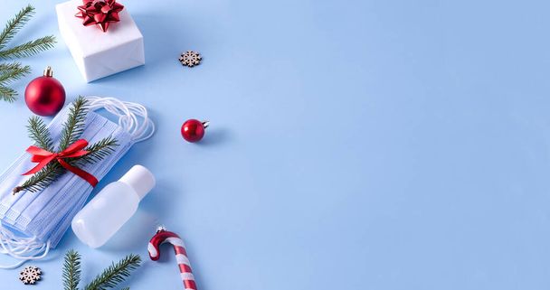 コロナウイルスのクリスマスバナーの概念。使い捨て、医療用マスク、防腐剤、ギフト、コピースペース、広告スペース、製品とクリスマスのおもちゃのスタック - 写真・画像