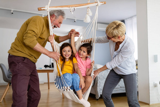 Beuatiful grandchildren having fun at home while playing with their grandparents - Фото, зображення
