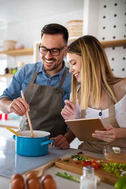 Happy couple enjoys and having fun preparing healthy meal together at home kitchen. - 写真・画像