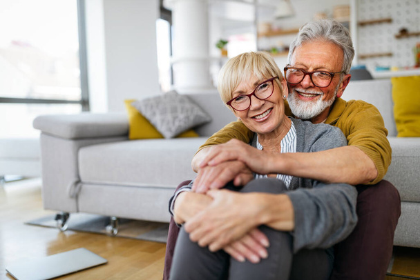 Happy senior couple hugging and enjoying retirement at home - Фото, изображение
