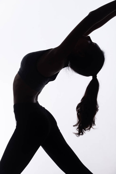 El cuerpo de silueta de Young Fitness Woman juega al sudor Yoga y estira el músculo para obtener una forma sexy y delgada. Alto contraste espacio de copia de fondo blanco - Foto, imagen