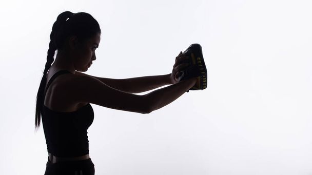 Σιλουέτα λεπτό σώμα του Young Fitness Woman γροθιά Πυγμαχία γάντια για την άσκηση τεντώνοντας το χέρι και φρουρά. Υψηλής αντίθεσης λευκό φόντο αντίγραφο χώρου - Φωτογραφία, εικόνα