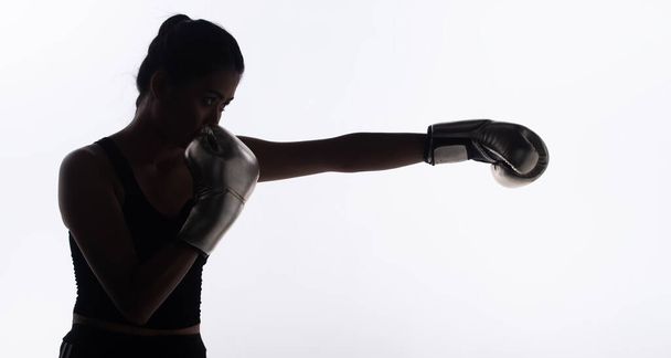 Σιλουέτα λεπτό σώμα του Young Fitness Woman γροθιά Πυγμαχία γάντια για την άσκηση τεντώνοντας το χέρι και φρουρά. Υψηλής αντίθεσης λευκό φόντο αντίγραφο χώρου - Φωτογραφία, εικόνα