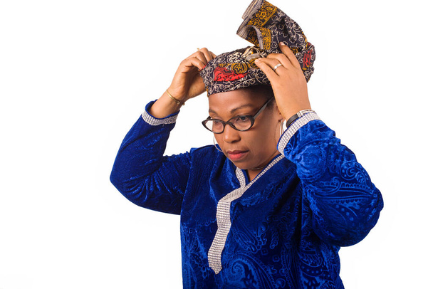 volwassen afrikaanse vrouw staan in bril op witte achtergrond aanpassen van haar sjaal. - Foto, afbeelding