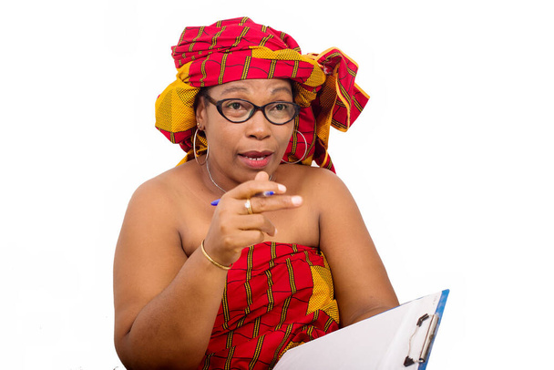 volwassen vrouw in lendendoek zitten op witte achtergrond kijken naar camera terwijl praten met pad notities in de hand. - Foto, afbeelding