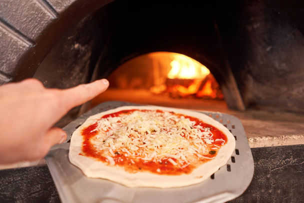 Billete crudo para hornear sabrosa pizza margherita en horno de leña tradicional en el restaurante Nápoles, Italia. pizza napolitana original. Carbón rojo caliente
. - Foto, imagen