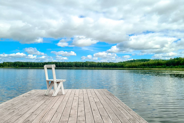 Blanco silla cubierta vacía en el muelle del lago. - Foto, Imagen